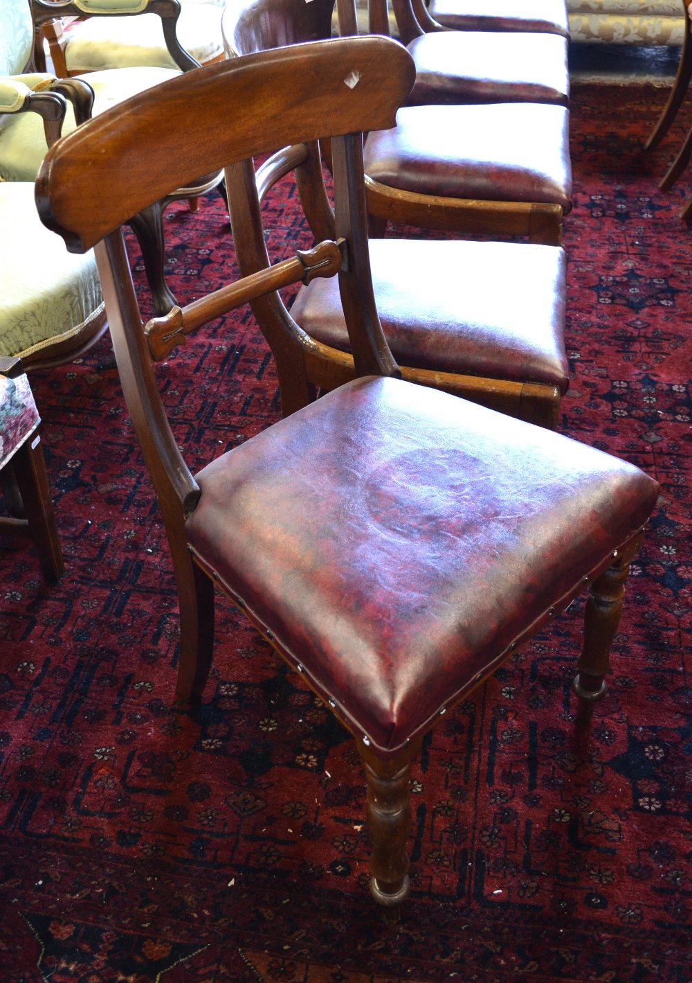 A harlequin set of five Victorian mahogany shaped bar-back chairs, each with matching red