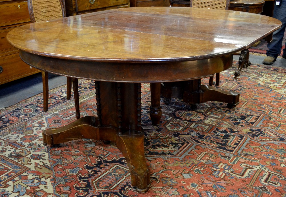 A George III mahogany extending dining table, the circular top accepting numerous insert leaves,