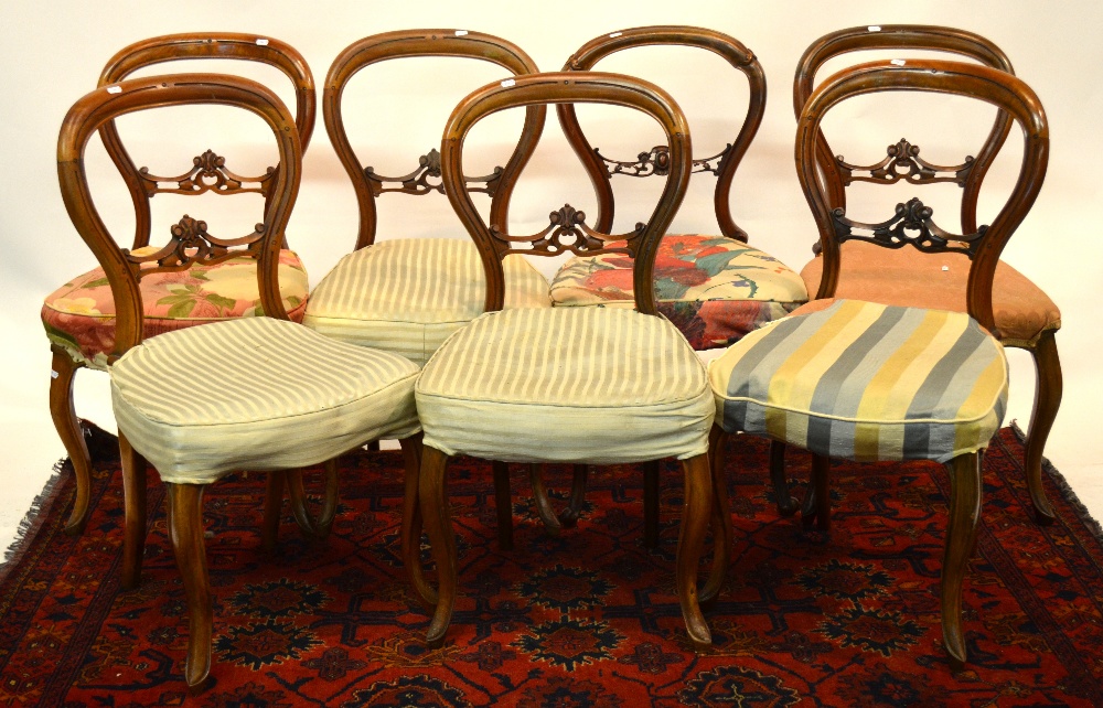 A set of six Victorian walnut balloon back side chairs, raised on cabriole front legs - to/w a