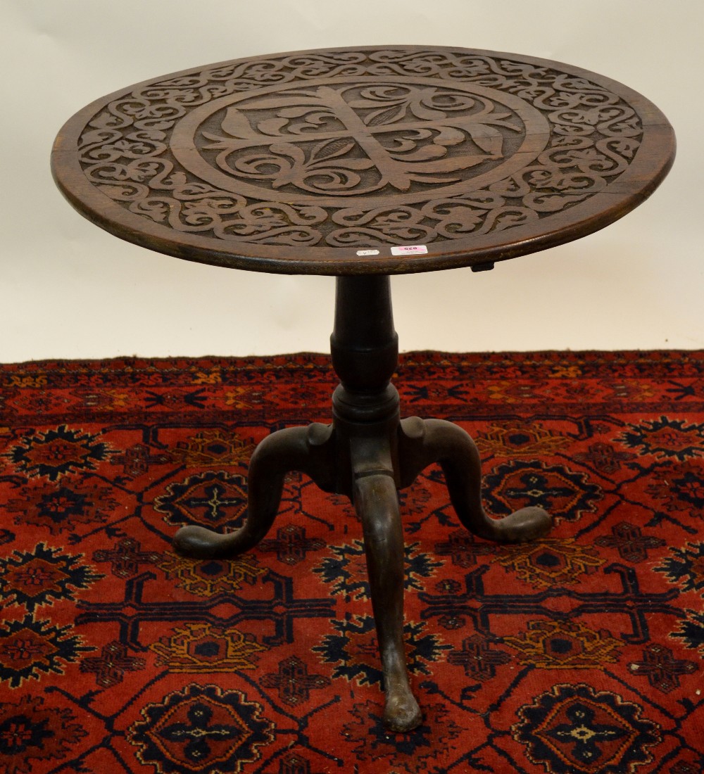 An 18th century oak tripod table, the circular tilt top carved with organic designs