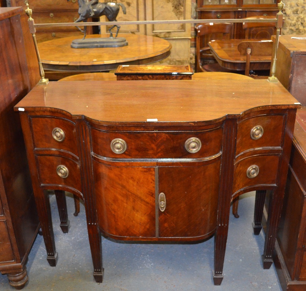 A compact Georgian style mahogany serpentine form sideboard, the top with raised brass splash rail