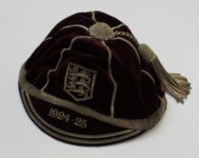 A maroon velvet Rugby cap with a silver thread sticking and tassel with three lions within a shield,