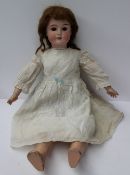A Schoenau & Hoffmeister bisque head doll with fixed brown eyes, open mouth and teeth, with a