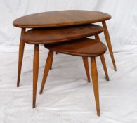 A nest of Ercol elm and beechwood pebble tables raised on splayed tapered supports