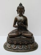 A bronze and copper seated Sino Tibetan Shakyamuni Buddha  seated on a double lotus base, monastic