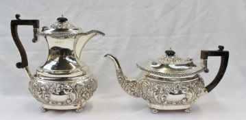 An Edwardian silver two piece tea set comprising a hot water pot and teapot, with floral, leaf and