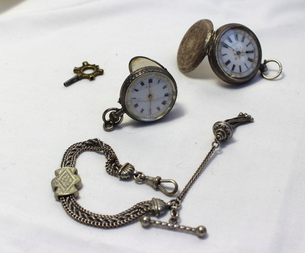 A silver fob watch with an enamel dial and Roman numerals together with another white metal fob