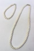 A pearl necklace with sixty six regular pearls to a silver clasp together with a similar bracelet