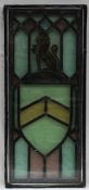 A leaded glass panel depicting a seated unicorn and a shield, encased between two panels of glass,