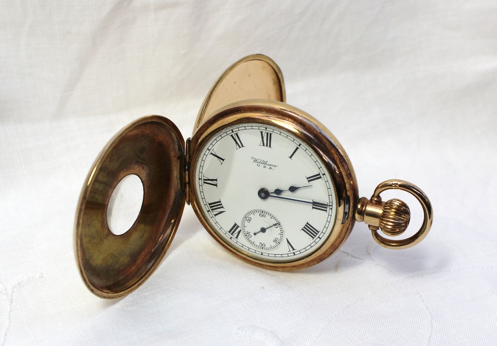 A yellow metal keyless wound half hunter pocket watch with an enamel dial, Roman numerals and