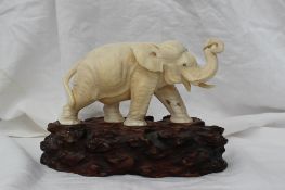 A late 19th century Japanese ivory elephant walking with raised trunk and mother of pearl eyes,
