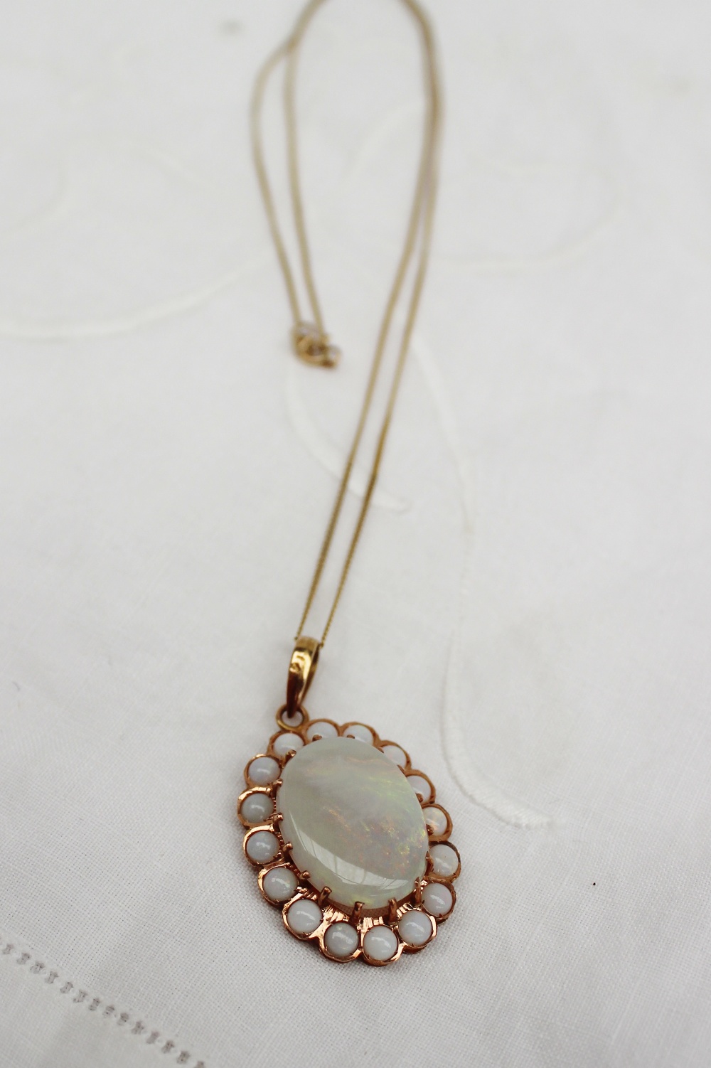 An opal pendant of large oval form surrounded by sixteen smaller circular opals to a yellow metal
