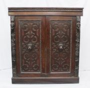 A 19th Century carved oak corner cupboard carved with figure heads and blind fret work decoration to