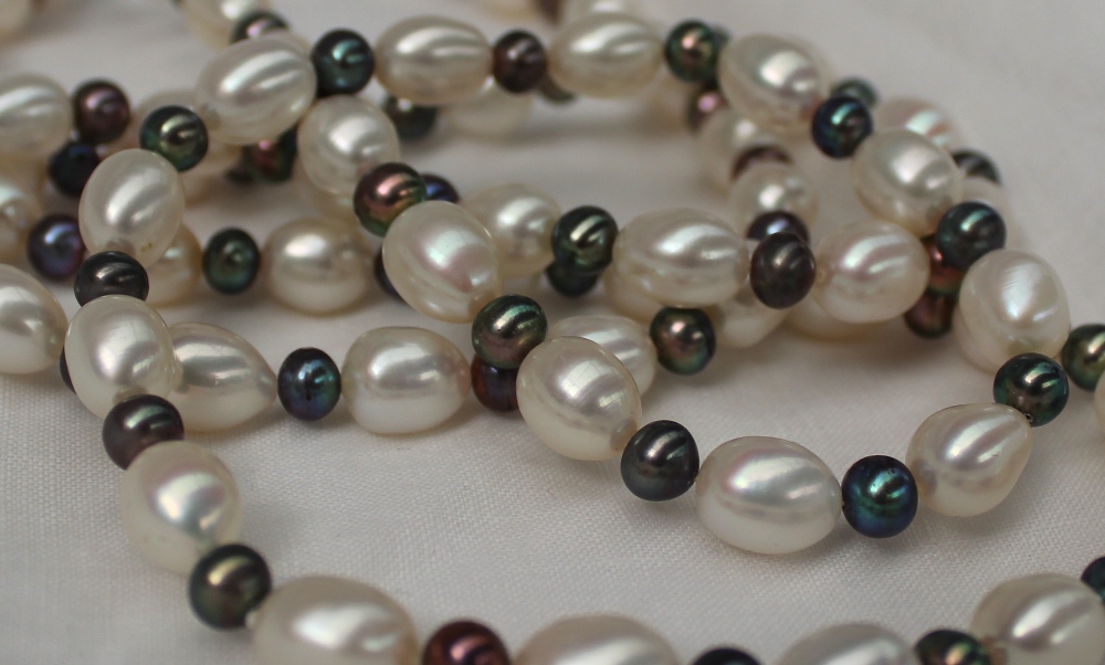 A pearl necklace set with pear shaped white pearls interspersed with spherical black pearls