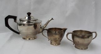 An Edward VII silver three piece teaset with a beaded rim and line decorated body on a spreading