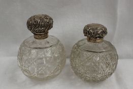 A matched set of late Victorian silver topped and cut glass scent bottles, embossed with flower