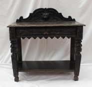A 19th century continental oak side table, the raised back with a lions head and leaves above a