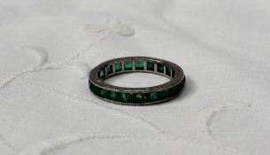 An emerald eternity ring set with baguette cut emeralds to a white metal setting, marked plat
