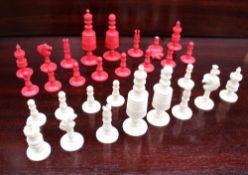 A carved and turned bone chess set, natural and stained red, the pawns with ball tops, the King