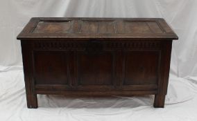 An 18th century oak coffer with a three panelled top, a carved frieze and a three panel front on