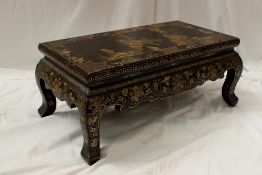 An oriental lacquer table, the rectangular top painted with rocks, bridge and figures, on shaped