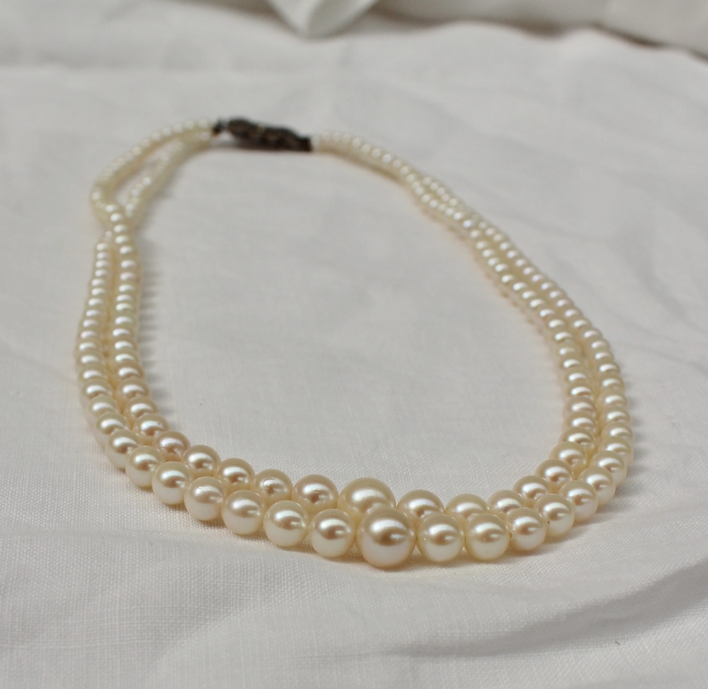 A two strand pearl necklace set with graduating pearls to white metal marcasite set clasp