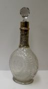 A George V silver mounted and cut glass decanter, with a stippled neck and a flattened flask like