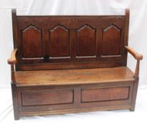 An 18th century oak settle, the four ogee panelled back above a hinged seat with two panels on