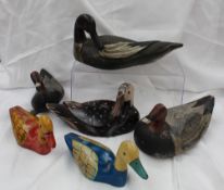 A carved wooden decoy duck with a lead weight attached at the base, together with two others similar