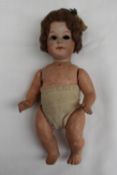 A Heubach bisque head doll with open eyes with a composition body and arms, 18cm long