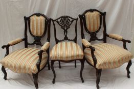 A pair of Edwardian mahogany elbow chairs with an upholstered shield shape and a pad seat on