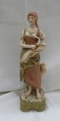 A Royal Dux figure of a young maiden holding a sheaf of corn and a sickle in muted colours