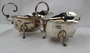A pair of George V silver sauce boats with a flared rim on shell capped legs with hoof feet,