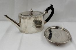 A George III Irish silver teapot of oval form, decorated with lines and swags, the shield under an