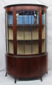 An Edwardian mahogany display cabinet of "D" shape with a central glazed door and glazed sides,