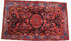 An Iranian blue ground rug with multiple flower heads and a floral interlaced border, 257cm x