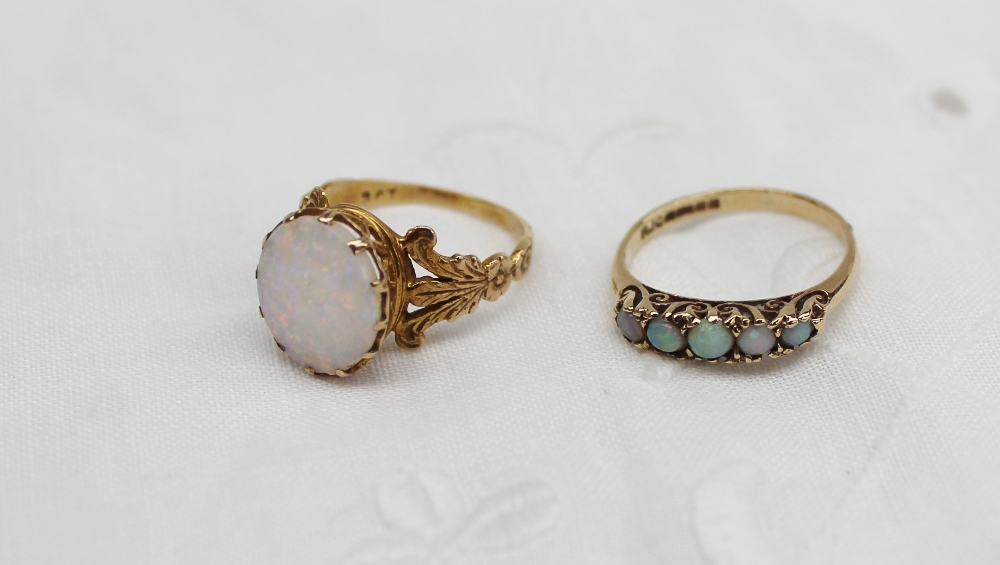 An opal ring of oval form to a yellow metal setting with feathers to the side of the shank marked