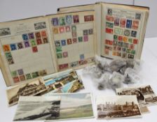 Two stamp albums containing world stamps, together with a small collection of scenic postcards and