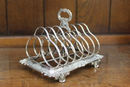 A Victorian silver toast rack, with six divisions, the base with a shell and C scroll border, on