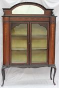 An Edwardian mahogany display cabinet, the raised back with a mirror above a pair of glazed doors