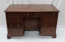 A George III mahogany desk, the rectangular top above an arrangement of eight drawers and a