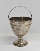 A George III silver swing handled pedestal urn, with a bead decorated handle and rim on a