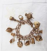 A 9ct yellow gold charm bracelet set with numerous charms including a bell, lantern, stein, mask,