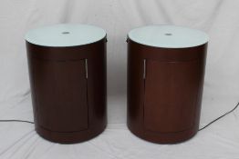 A pair of modern cylindrical uplit bedside cabinets, with a single door, 43.5cm diameter x 56.5cm