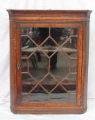 A 19th century oak corner cupboard, the moulded cornice above a glazed door with glazing bars on a