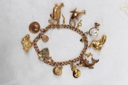 A 9ct yellow gold charm bracelet set with numerous charms including an oyster shell, dolphin,