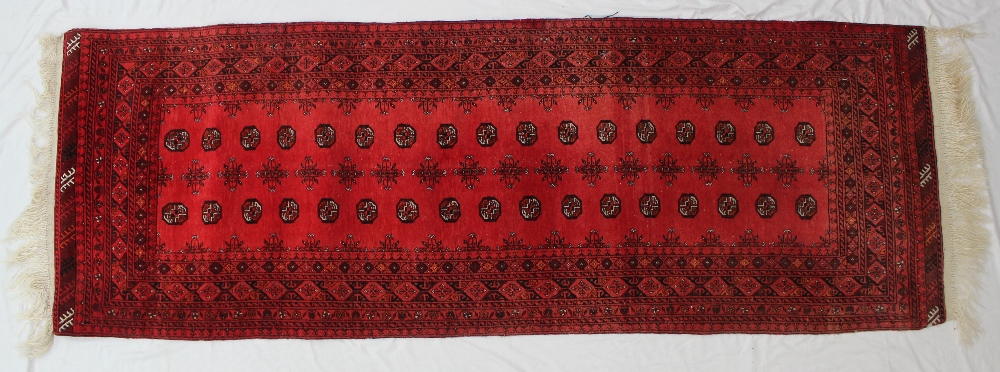 A Turkoman runner with multiple guls to a red ground, with bands of repeating stylised flower heads,