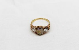 An opal and diamond ring set with a central oval opal measuring 10mm x 8mm, flanked by two cushion