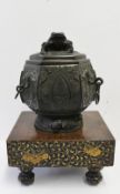 A Japanese bronze urn and cover, of hexagonal form with a toad finial, the panelled sides