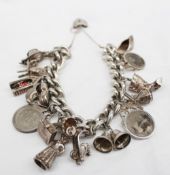 A silver charm bracelet  set with numerous charms including a slipper, coins, windmill, moped,